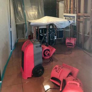 Industrial air movers and dehumidifiers strategically placed to dry a water-damaged home by EZ Water Damage Restoration Services.